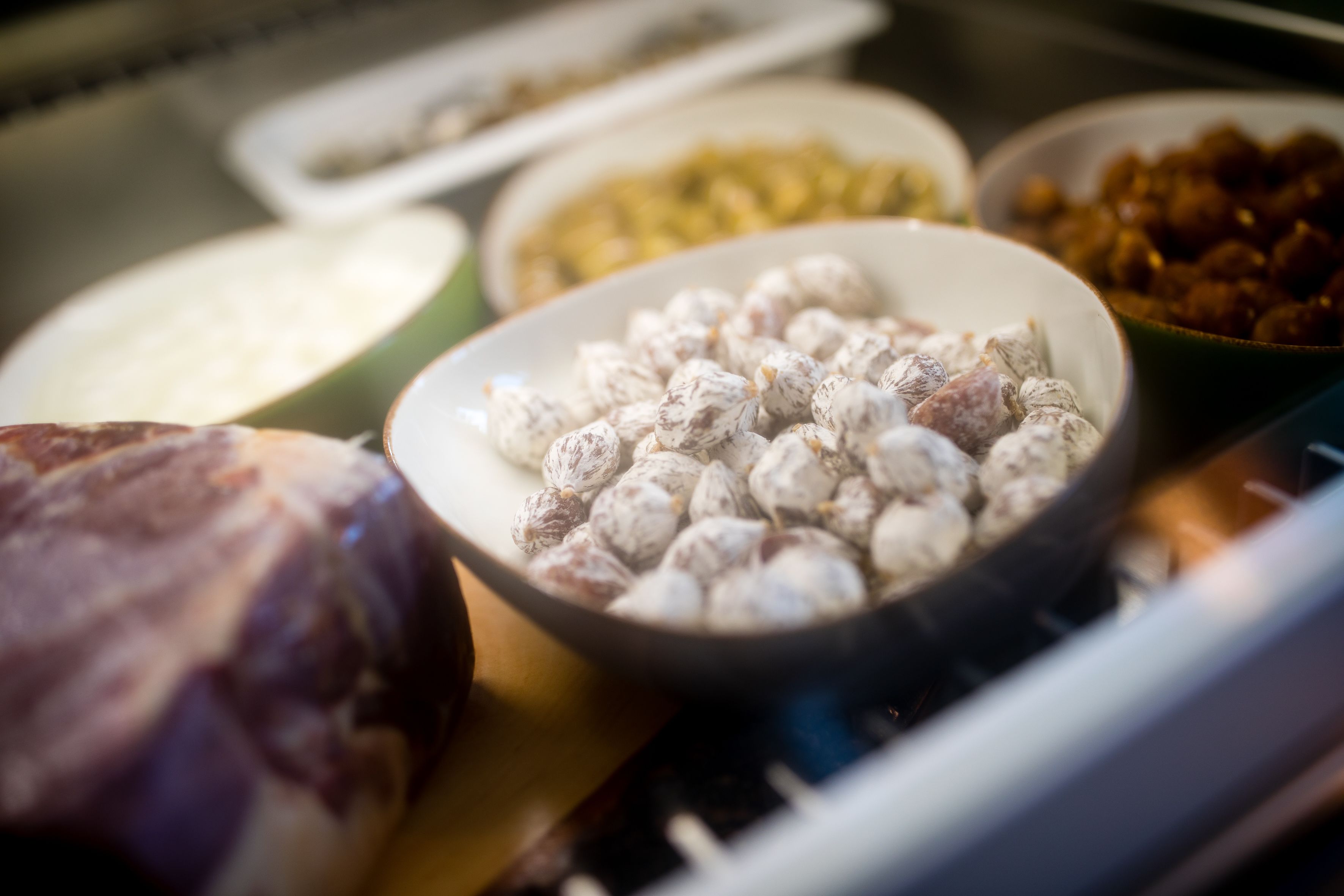 Variedad de alimentos, incluyendo un tazón de nueces y un gran trozo de carne, sobre una mesa.