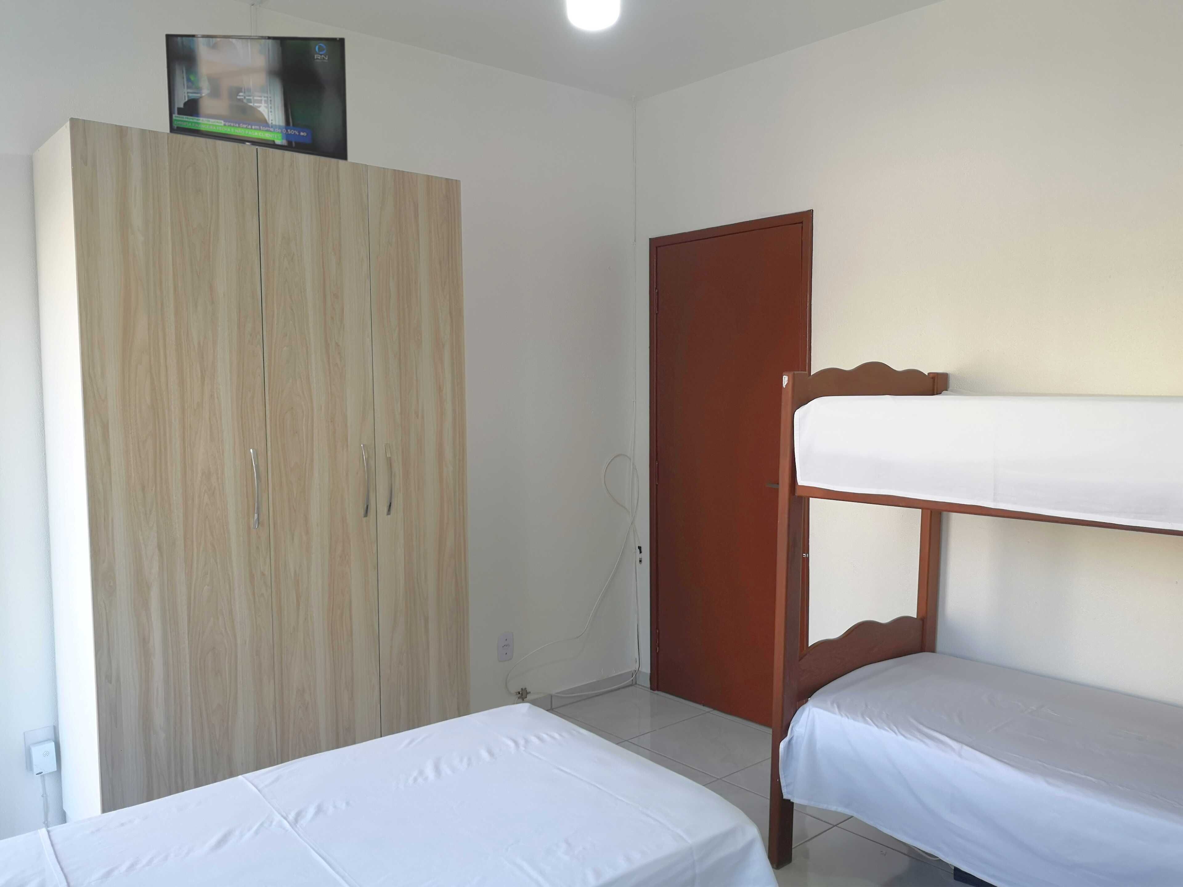 A room with a wooden wardrobe, a door, and a bunk bed.