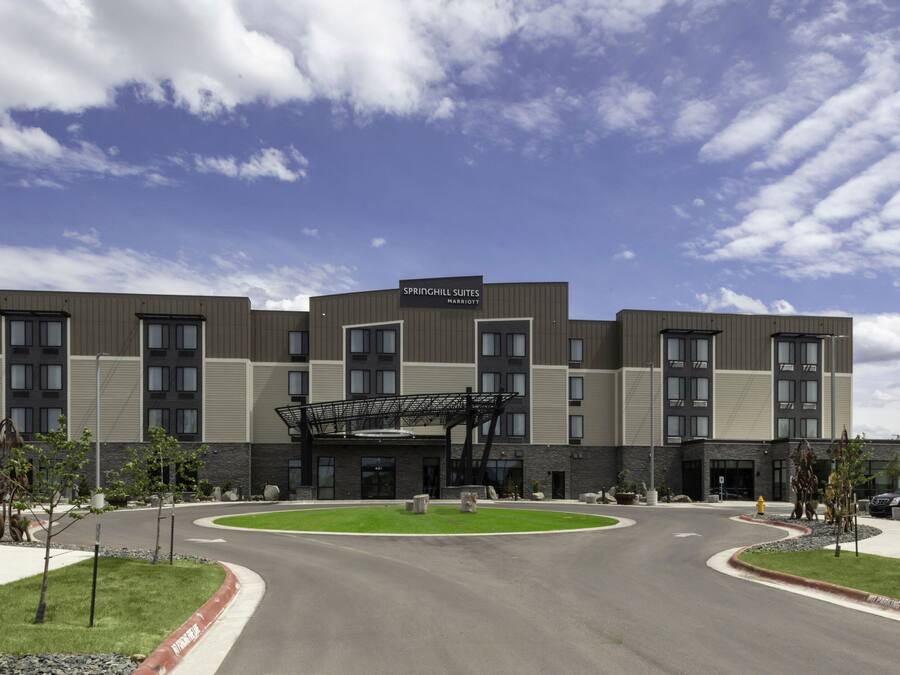 A modern hotel with a flat roof, multiple entry points, and a landscaped front yard.