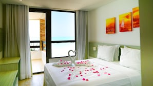 A hotel room with a bed, a balcony, and a view of the ocean. - Waterfront Apart Hotel (Maceió)