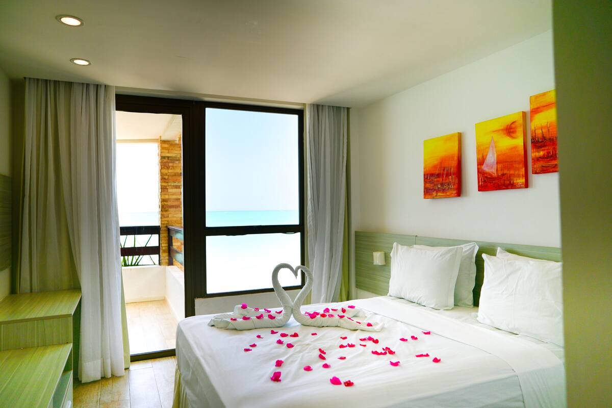 Ein Hotelzimmer mit Bett, Balkon und Meerblick.