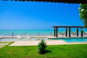 Ein Poolbereich mit Liegestühlen und einer Pergola mit Blick auf den Ozean.