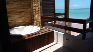 A bathroom with a wooden bathtub, a wooden bench, and a view of the ocean. - Waterfront Apart Hotel (Maceió)