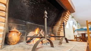 A fireplace with a brick surround, a metal stand, and a clay pot. - Hotel Rural El Retiro de San Pedro (Arenas de San Pedro)