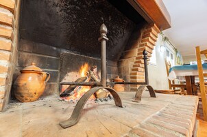 Una chimenea con revestimiento de ladrillo, un soporte de metal y una maceta de barro.