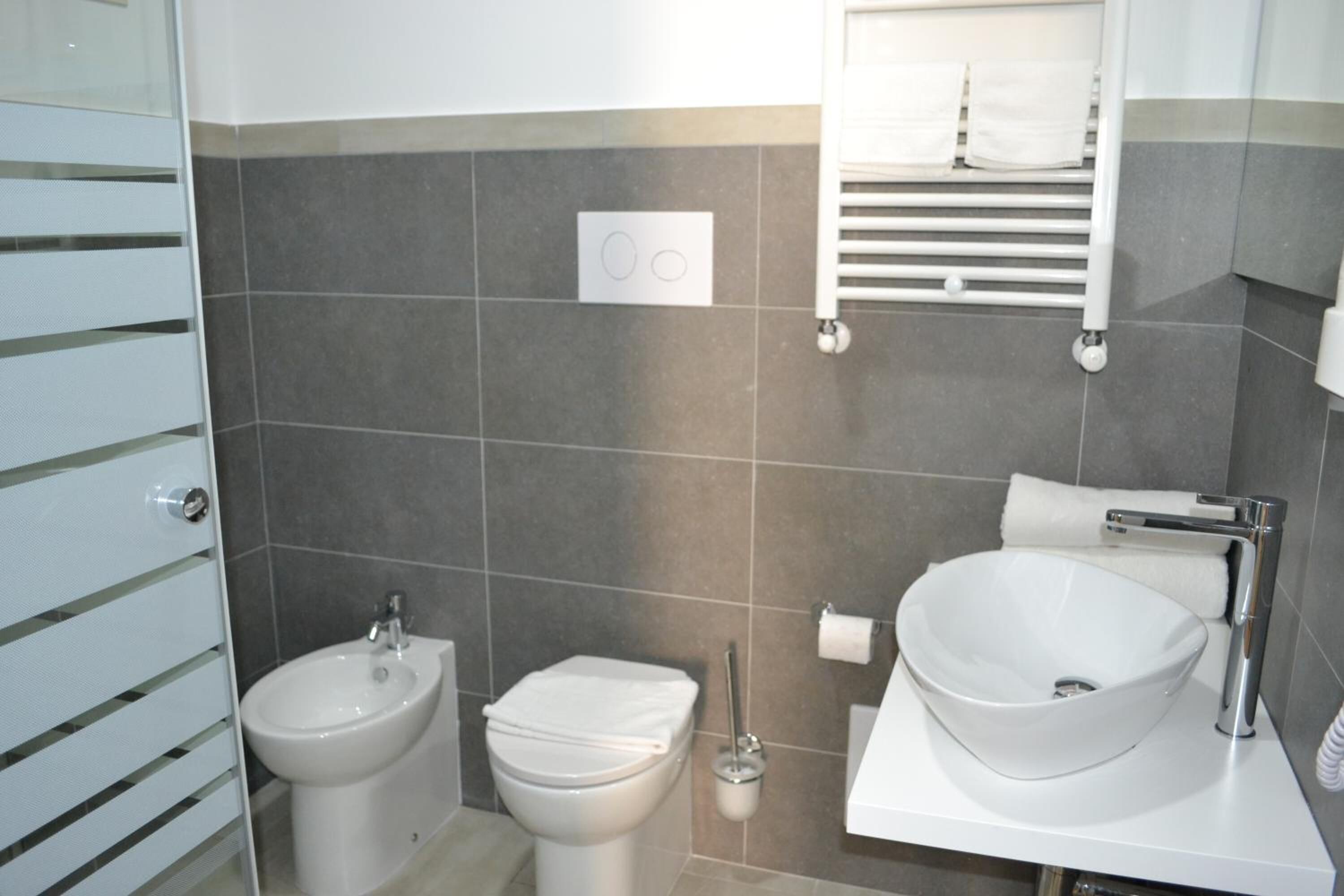 A modern bathroom with a bidet, toilet, and a large vessel sink.