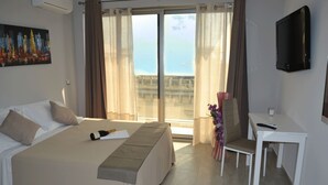 Habitación de hotel con cama, escritorio, silla, televisión y vistas al exterior.