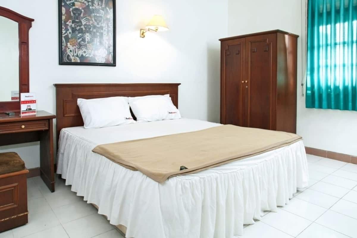 Un dormitorio ordenado con cama, armario de madera, escritorio y lámpara de pared.