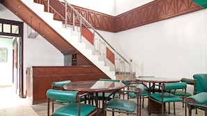 A lobby with a staircase, green upholstered chairs, and a wooden reception desk. - RedDoorz near UPN Veteran (Surabaya)