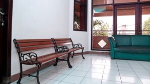 A room with a wooden bench, a green sofa, and a large window with a view of greenery outside. - RedDoorz near UPN Veteran (Surabaya)
