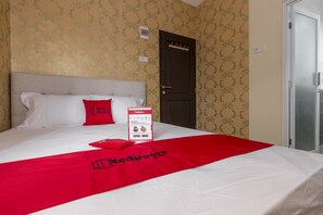 Een hotelkamer met een bed, een rode plaid en een brochure van Red Door op het bed.
