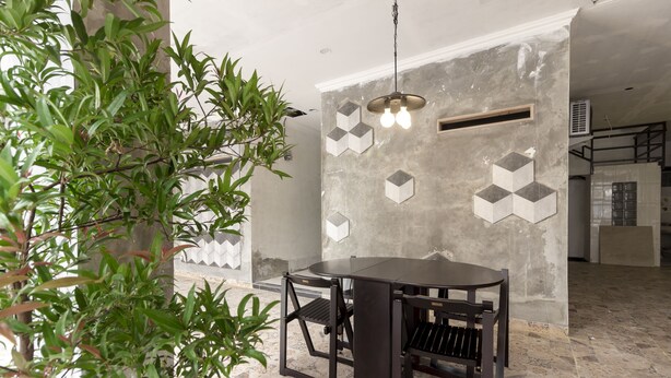 Un espace repas comprenant une table et des chaises, un luminaire suspendu et un mur orné de motifs géométriques.