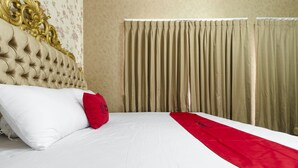 Un lit avec une couvre-lit blanche et rouge, un oreiller rouge et une tête de lit dorée.