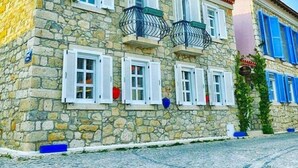 A stone building with multiple windows, a red-tiled roof, and a sign indicating a hotel. - Simira Hotel (Cesme)