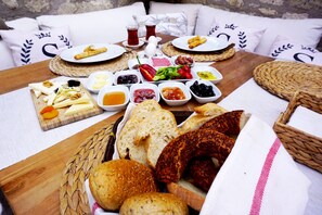 A table set with various foods including bread, cheese, and dips, suggesting a meal setup outdoors. - Simira Hotel (Cesme)