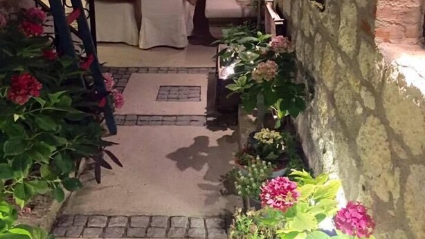 A cozy outdoor seating area with stone walls, a table set for dining, and potted plants. - Simira Hotel (Cesme)