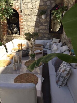 A cozy outdoor seating area with a stone wall backdrop, wicker furniture, and potted plants. - Simira Hotel (Cesme)