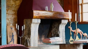 A cozy room with a stone fireplace, bookshelves, and a green chair. - Pousada Casa das Fontes (Tiradentes)