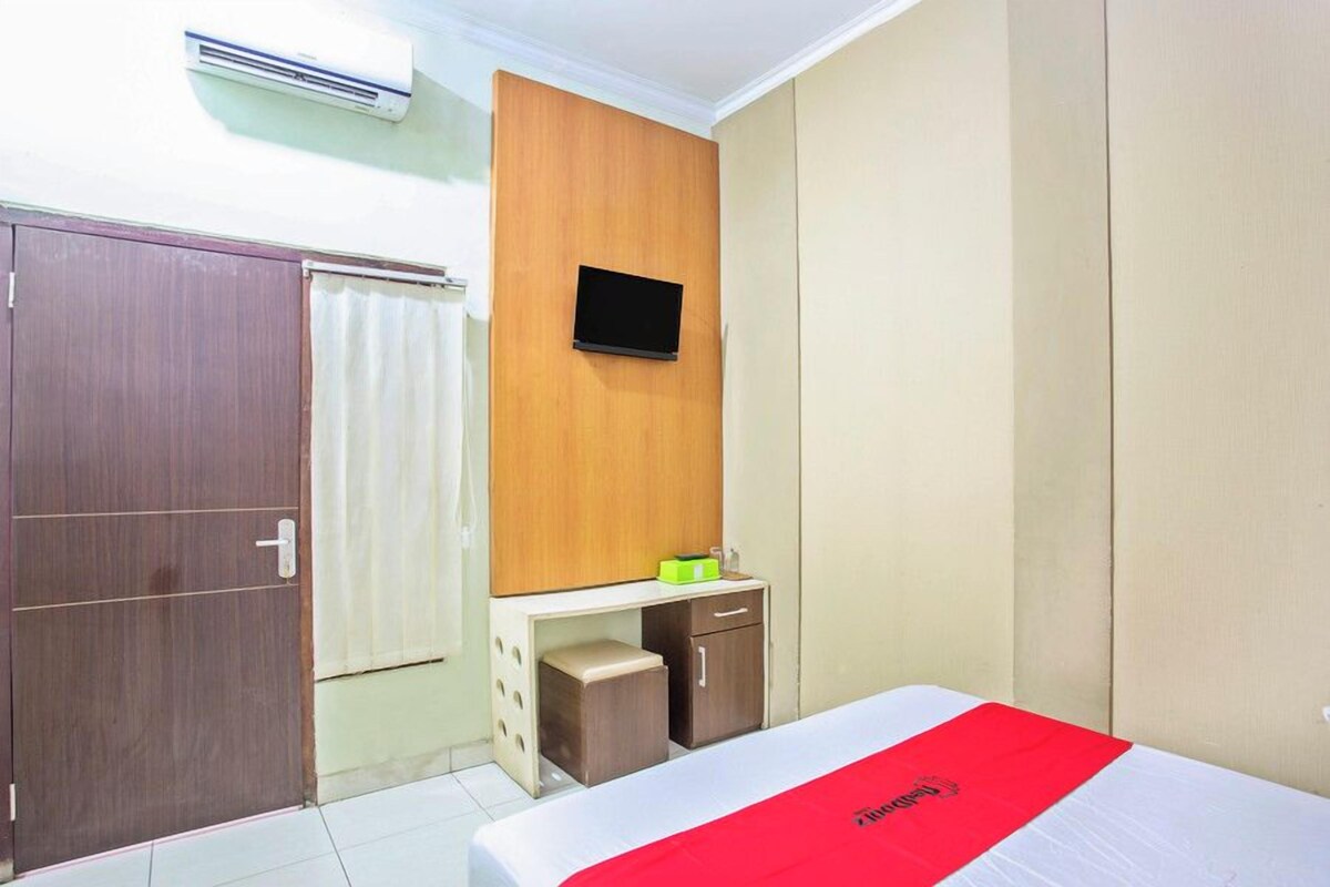 Une chambre d’hôtel comprenant un lit, un bureau avec une chaise, une armoire et un téléviseur fixé au mur.