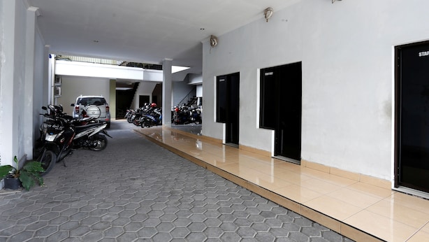 A clean, modern hallway with a tiled floor, several doors, and parked motorcycles. - RedDoorz near Adisucipto Airport 3 (Kalasan)