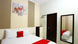 A hotel room with a bed, a red pillow, a white bedspread, a wall-mounted mirror, and a door. - RedDoorz near Adisucipto Airport 3 (Kalasan)