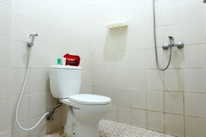 Une salle de bain équipée de toilettes, d’une douche et d’un porte-savon fixé au mur.