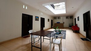 A spacious room with a skylight, a dining table with chairs, a red sofa, and a small potted plant. - RedDoorz near Adisucipto Airport 3 (Kalasan)