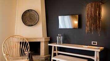 A room with a wooden chair, a fireplace, a wall-mounted TV, and a hanging light fixture.