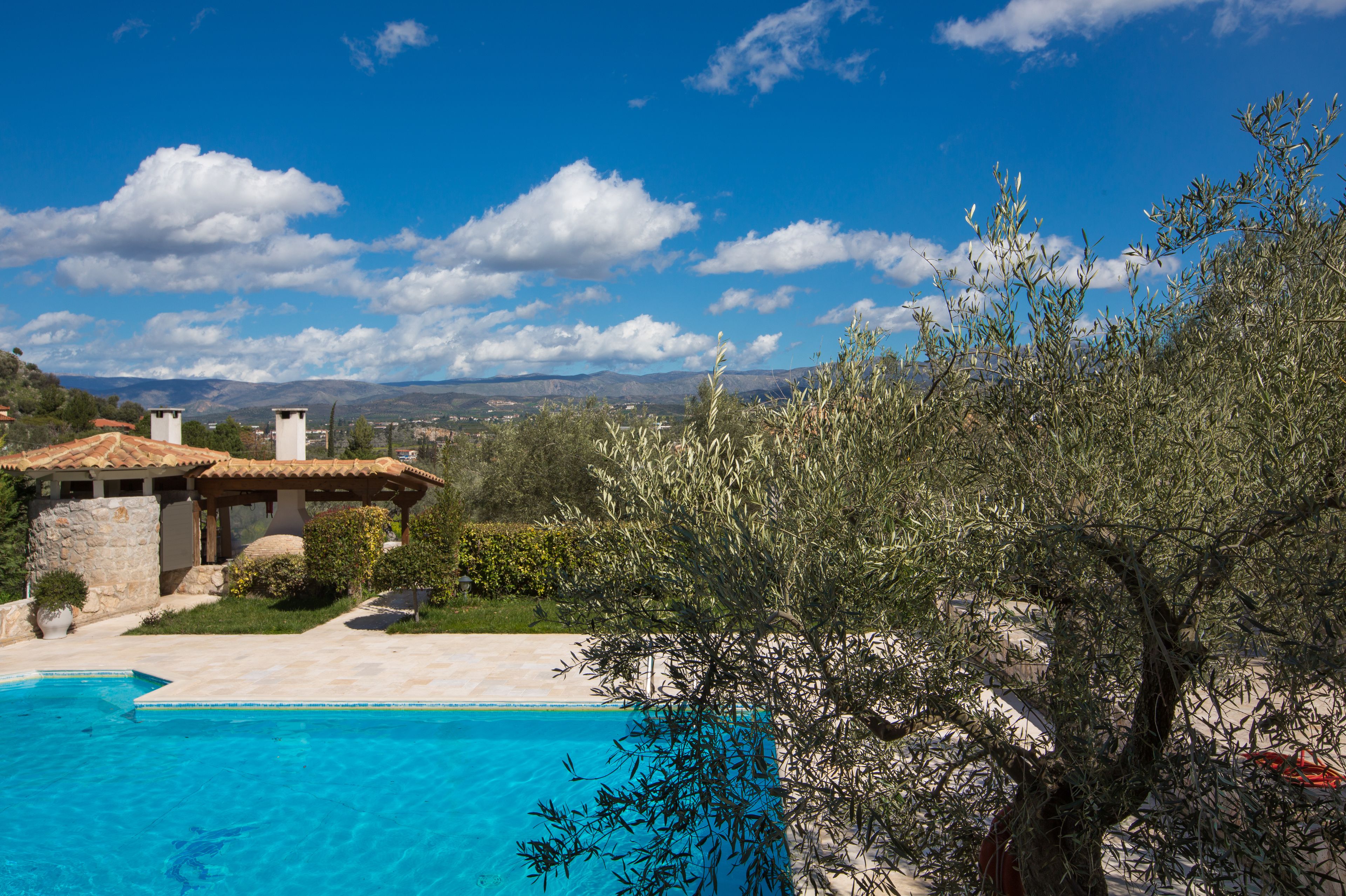 A pool area with a clear blue sky and mountains in the background.