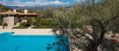 A pool area with a clear blue sky and mountains in the background.