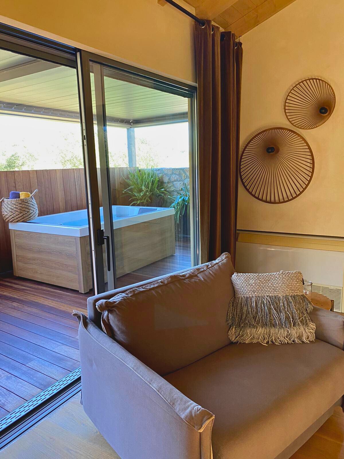 A modern living room with a sliding glass door leading to a pool area, a brown leather sofa, and two wall-mounted decorative lamps.