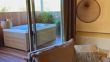 A modern living room with a sliding glass door leading to a pool area, a brown leather sofa, and two wall-mounted decorative lamps.