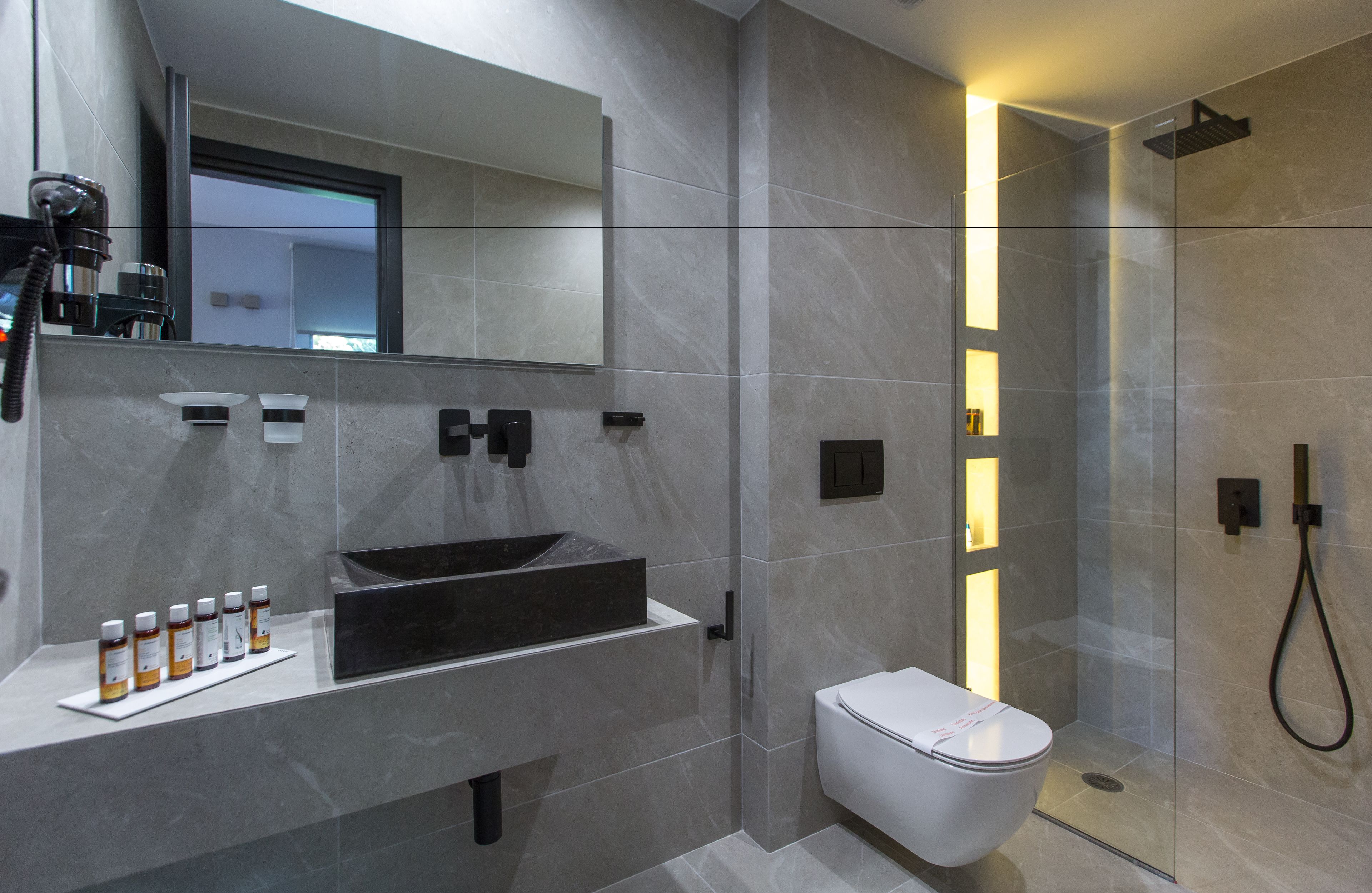 A modern bathroom with a large mirror, a vessel sink, and a toilet.