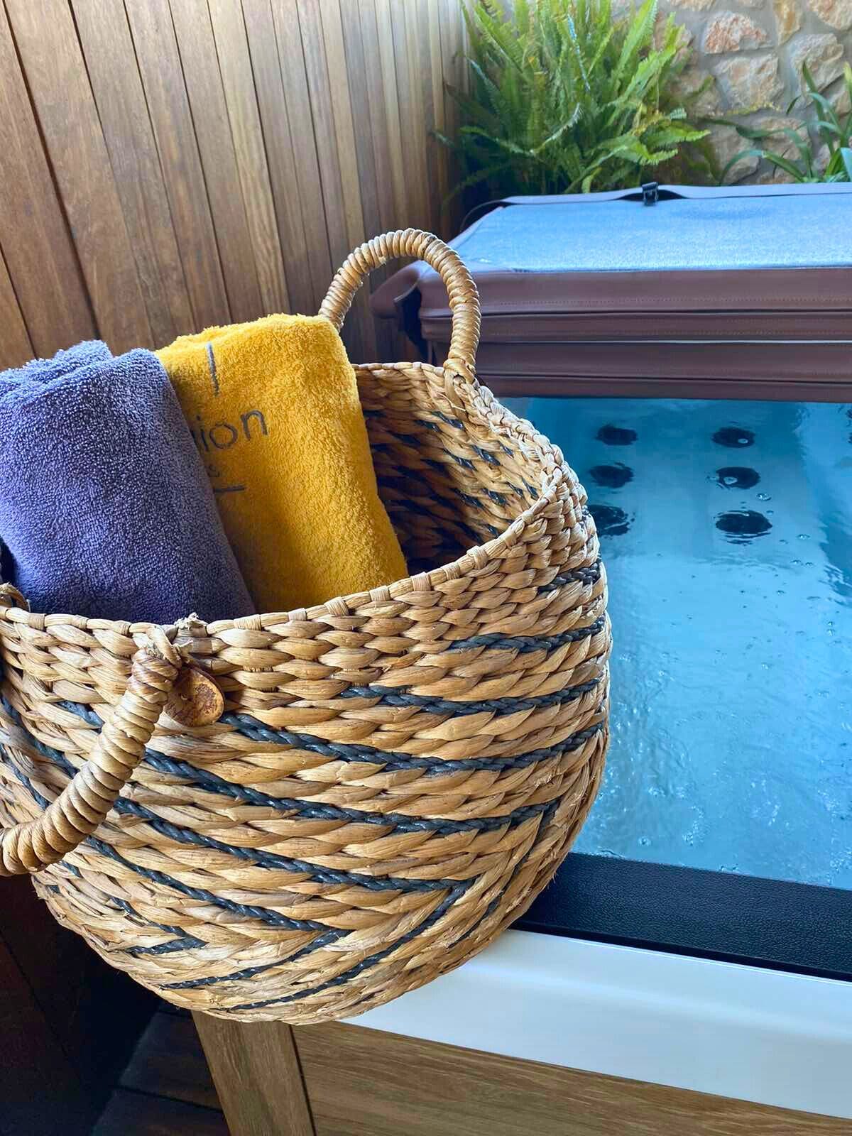 Una cesta tejida con toallas junto a una bañera de hidromasaje.