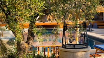 Un área junto a la piscina con una jardinera de piedra, una mesa de metal y sillas de descanso.