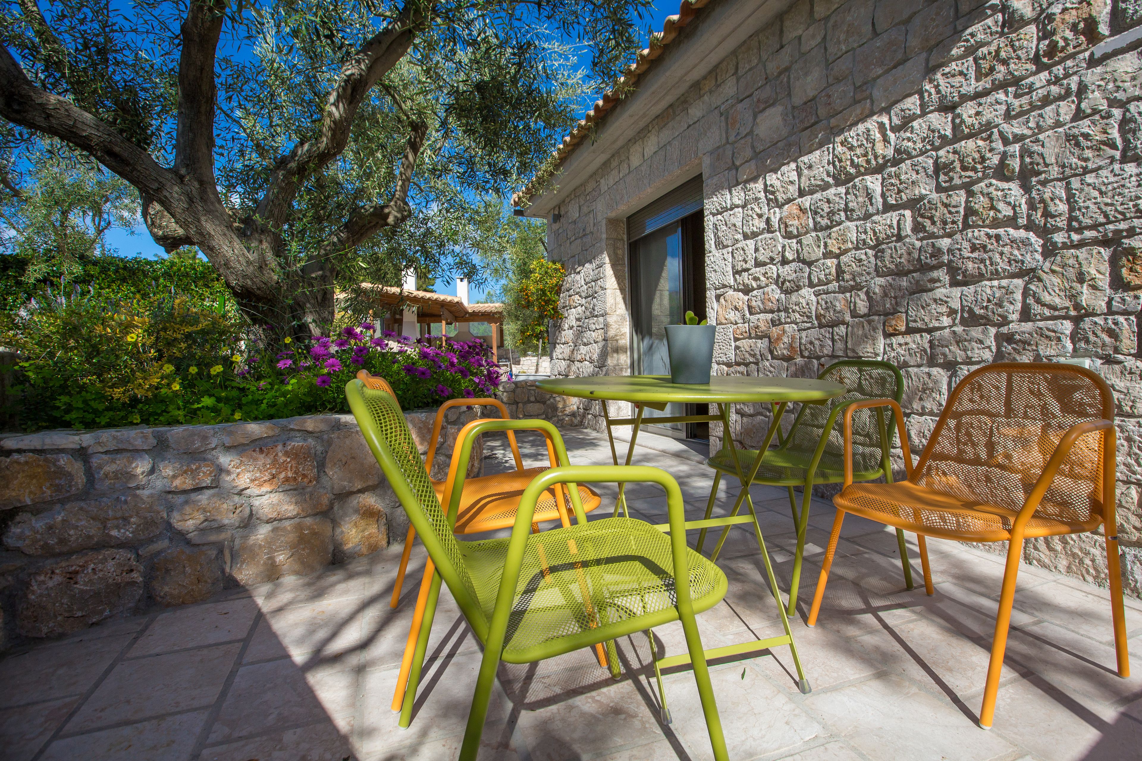 An outdoor patio with stone walls, a stone table, and metal chairs.
