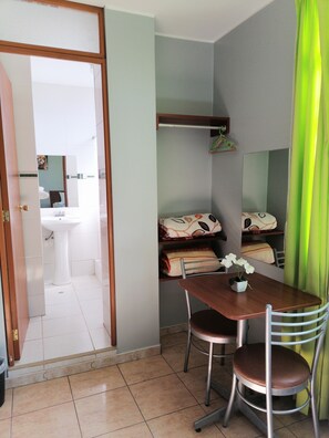 Cozy retreat with a compact dining area, comfortable bed, and mirror above the table.