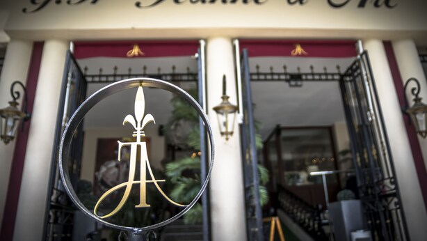 A hotel entrance with a sign reading "G.H Jeanne d'Arc" and a decorative metal archway. - Grand Hotel Jeanne d'Arc (Lourdes)