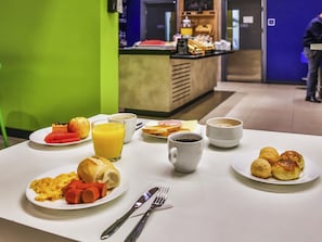 Ein Frühstückstisch mit Tellern voller Essen, einem Glas Orangensaft und einer Tasse Kaffee.