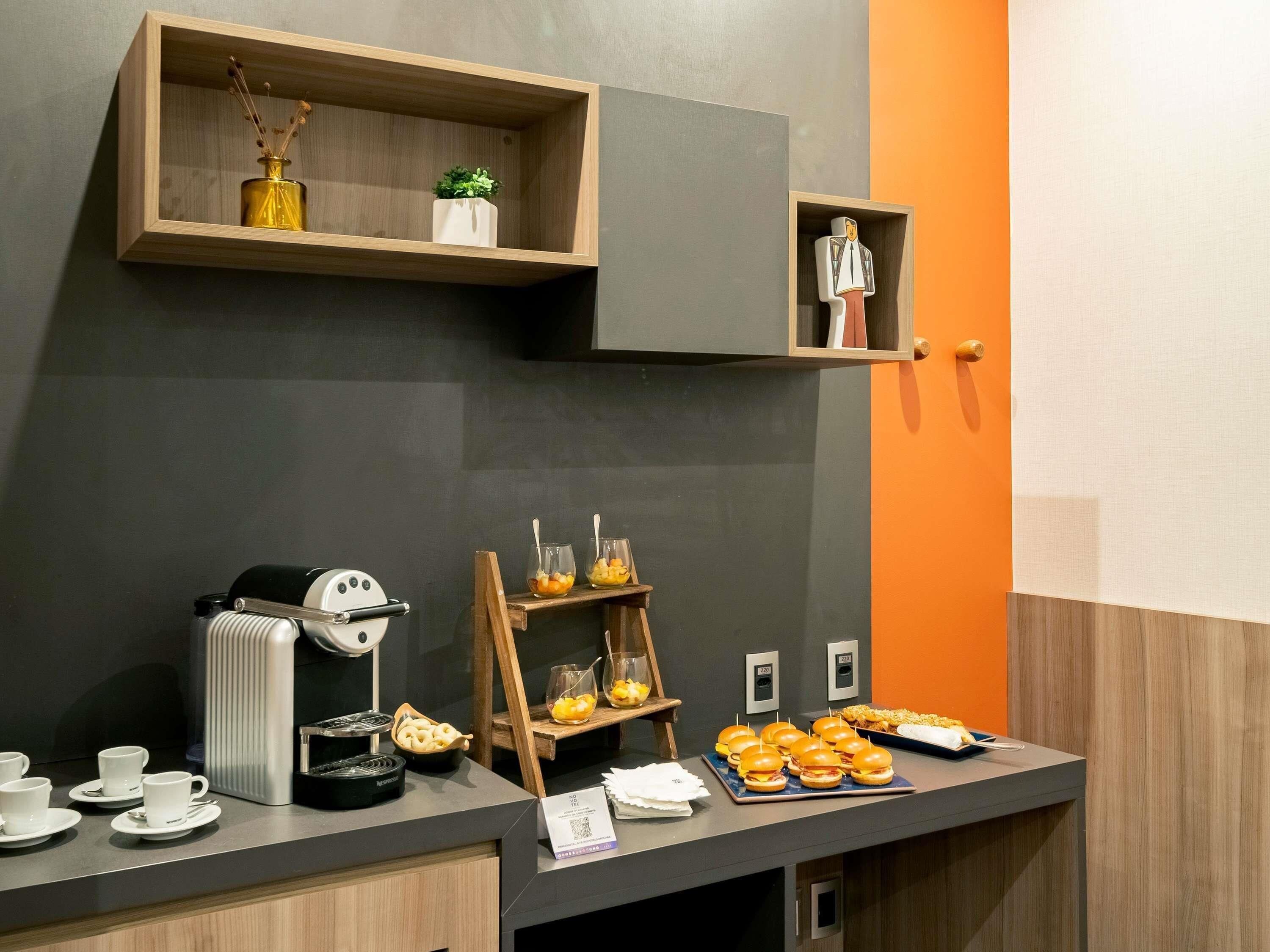 Un bufé de desayuno con máquinas de café, una exposición de frutas y una estación de sándwiches.