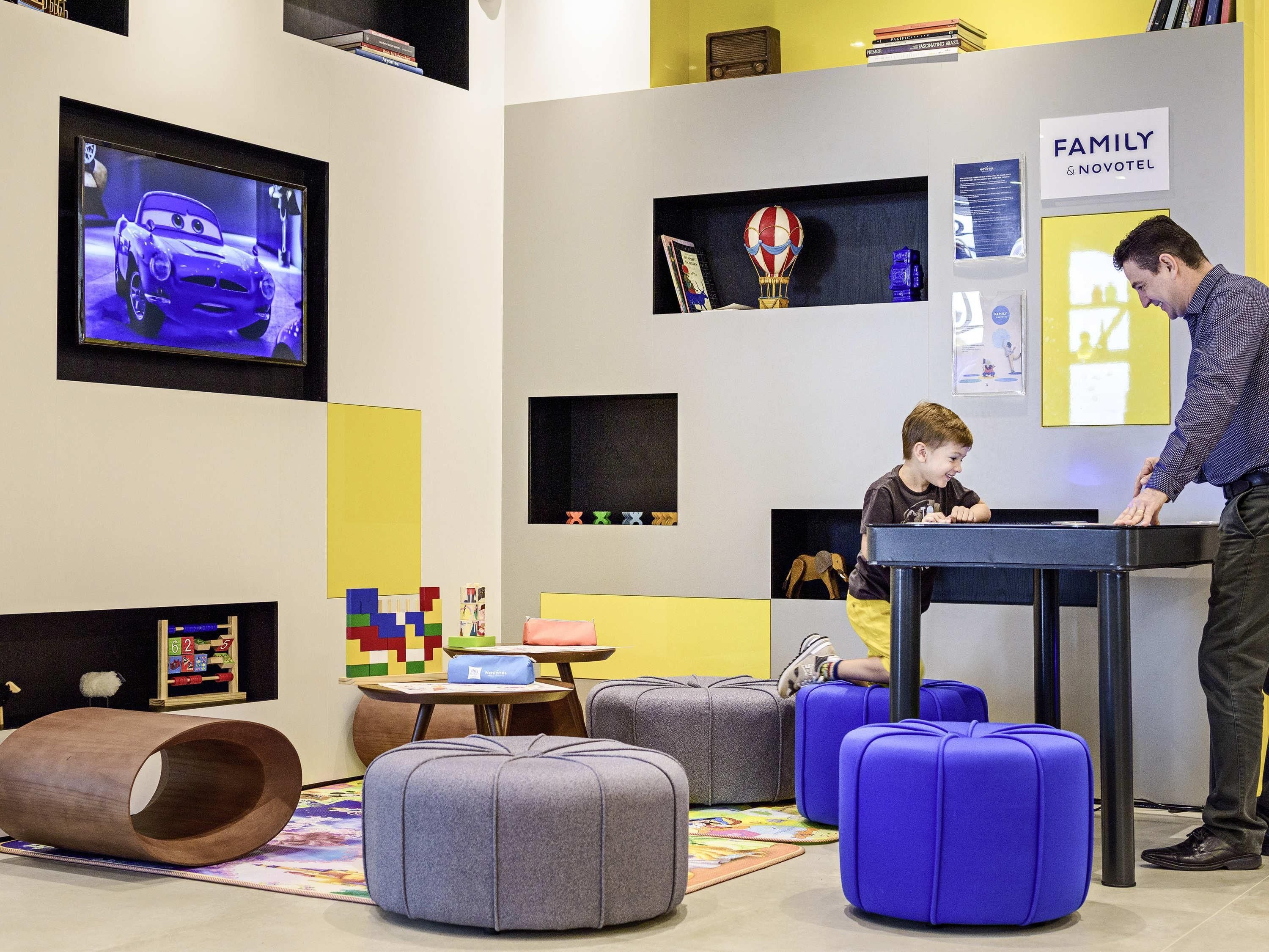 Eine moderne Hotelhalle mit Fernseher, Kinderspielbereich und familienfreundlicher Atmosphäre.