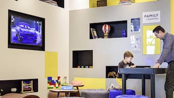 Eine moderne Hotelhalle mit Fernseher, Kinderspielbereich und familienfreundlicher Atmosphäre.