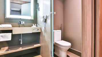 A modern bathroom with a glass shower enclosure, a toilet, a sink with a mirror, and a towel rack.