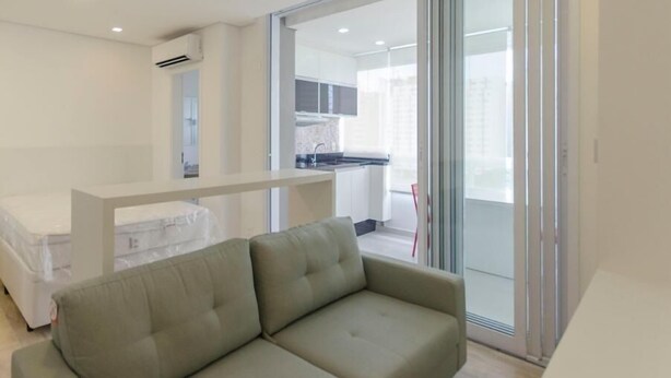 Ein modernes Apartment mit einer Couch, einer Küchenzeile und einer Glastür zum Balkon.