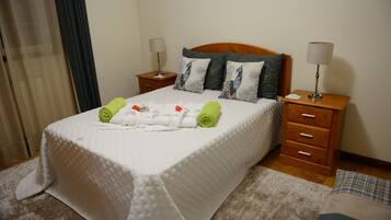 A neatly made bed with a white quilt, two nightstands with lamps, and a wooden headboard.