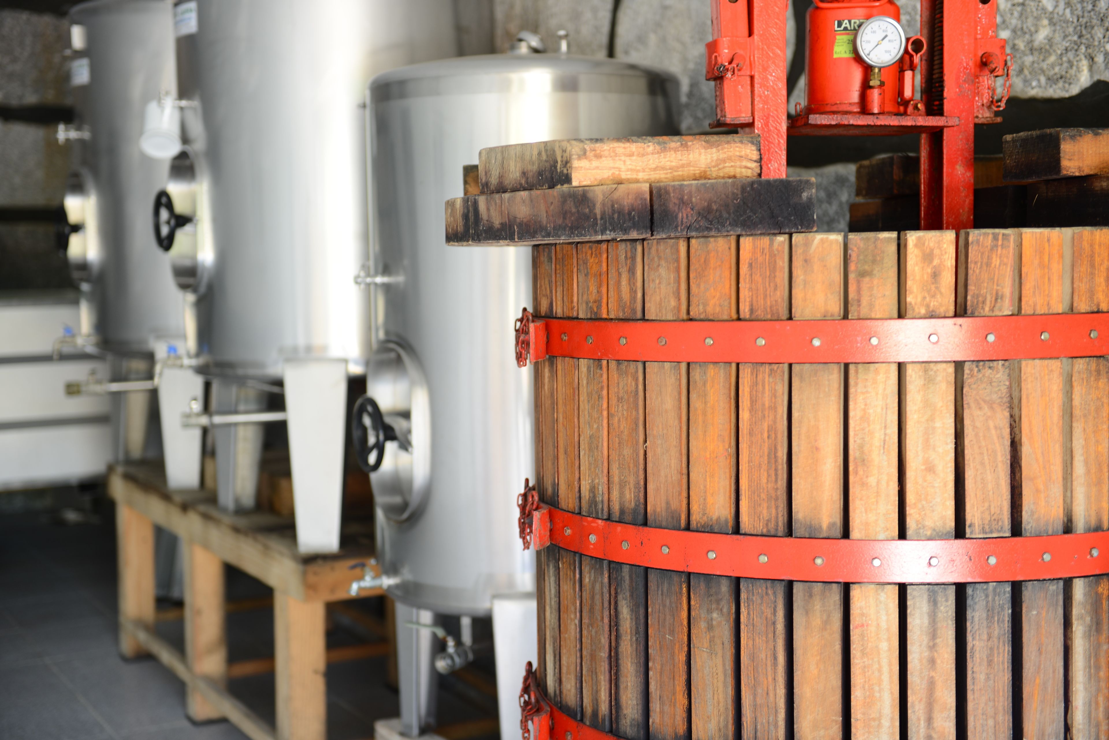 Industrial brewing tanks and a wooden barrel with metal bands.
