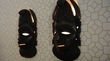 Zwei schwarze Masken mit Leuchten an einer Wand mit geometrischem Muster.