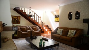 A living room with a staircase, two sofas, a coffee table, and decorative pillows. - AboimHouse (Amarante)