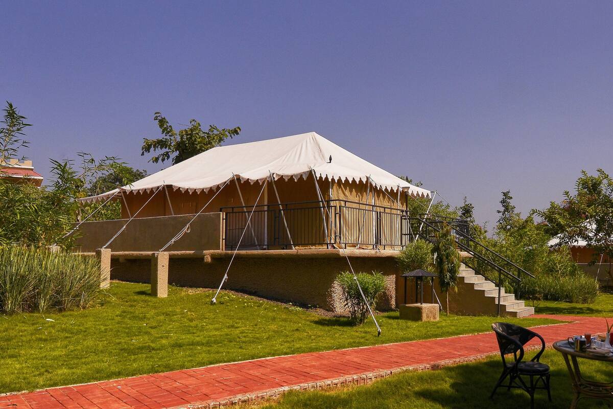 A tented structure with a balcony, a staircase, and a brick pathway.