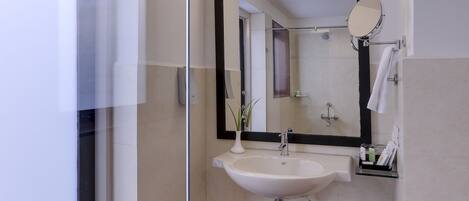 Une salle de bain moderne avec un grand miroir, un lavabo et un espace douche.